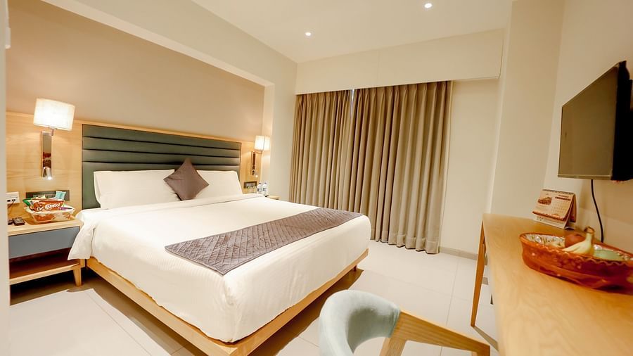An image of a bedroom with a bed, bedside tables with lamps and a flat TV screen at Pride Resort Ambaji